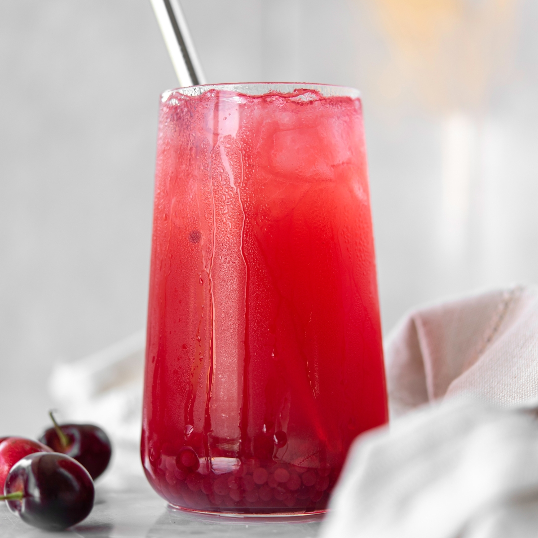 Red beverage with cherries in glass