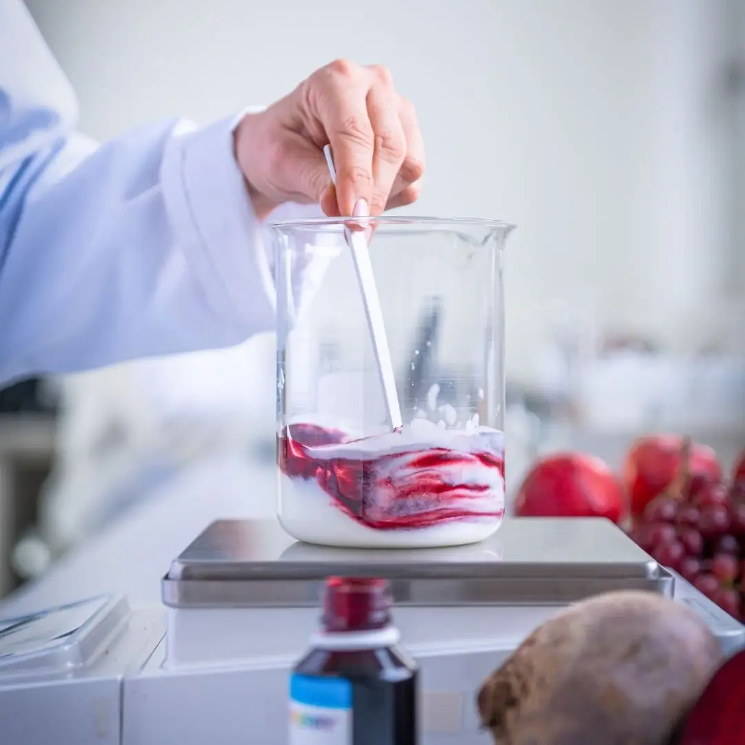Woman stirring red color into yoghurt in a lab